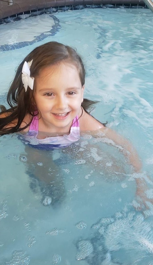 a young girl swimming in a pool with a big smile on her face
