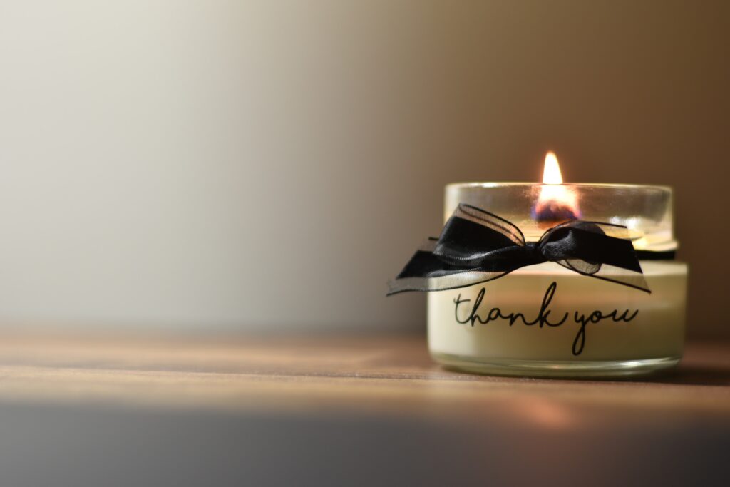 An image of a candle that says "Thank you" with a black ribbon.