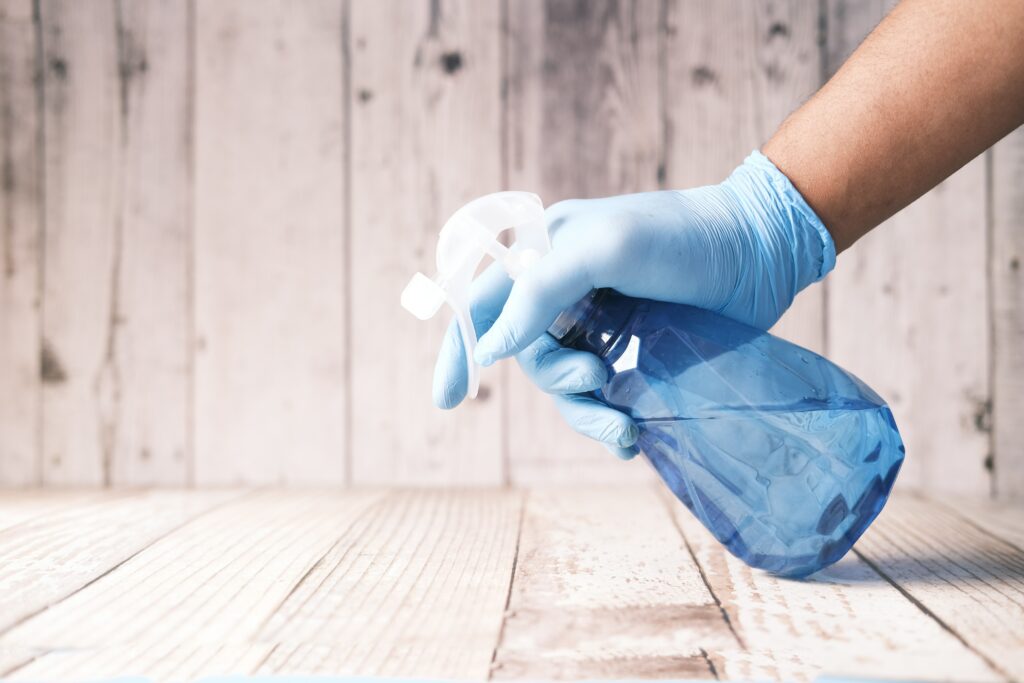 An image of a hand that is holding a sprayer that's spraying the floor.