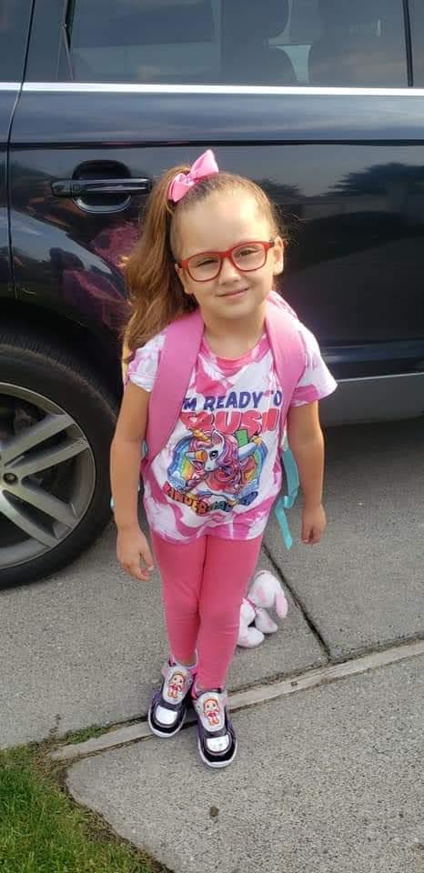 a young girl wearing glasses and a pink backpack